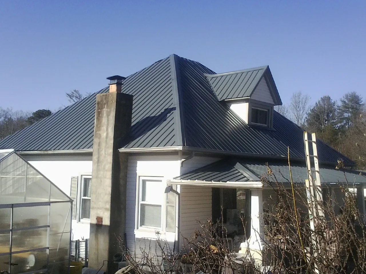Dark blue standing seam metal roof on a white farmhouse with dormer — Slate & Tile Roof Repair by Roofing Brothers in Chester Springs
