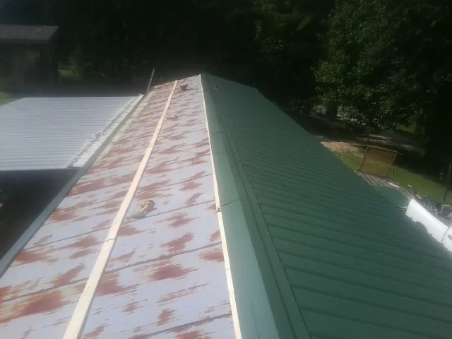 Old rusted panels beside newly installed green metal roofing — Wind Damage Roof Repair by Roofing Brothers in Chester Springs