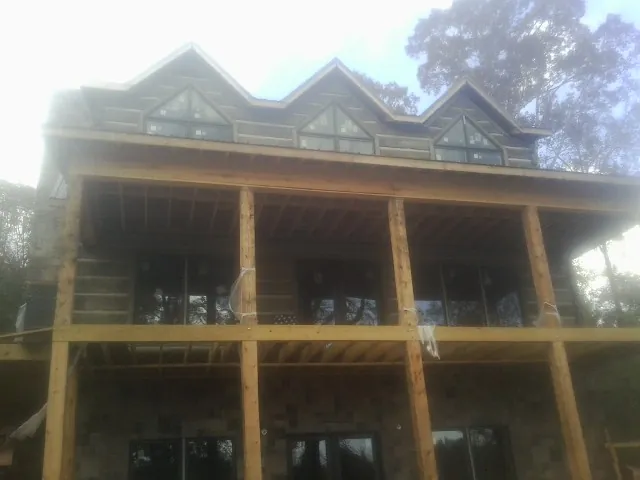 Dormers and porch framing on a large log home under construction — Roof Coating work by our crew in Chester Springs