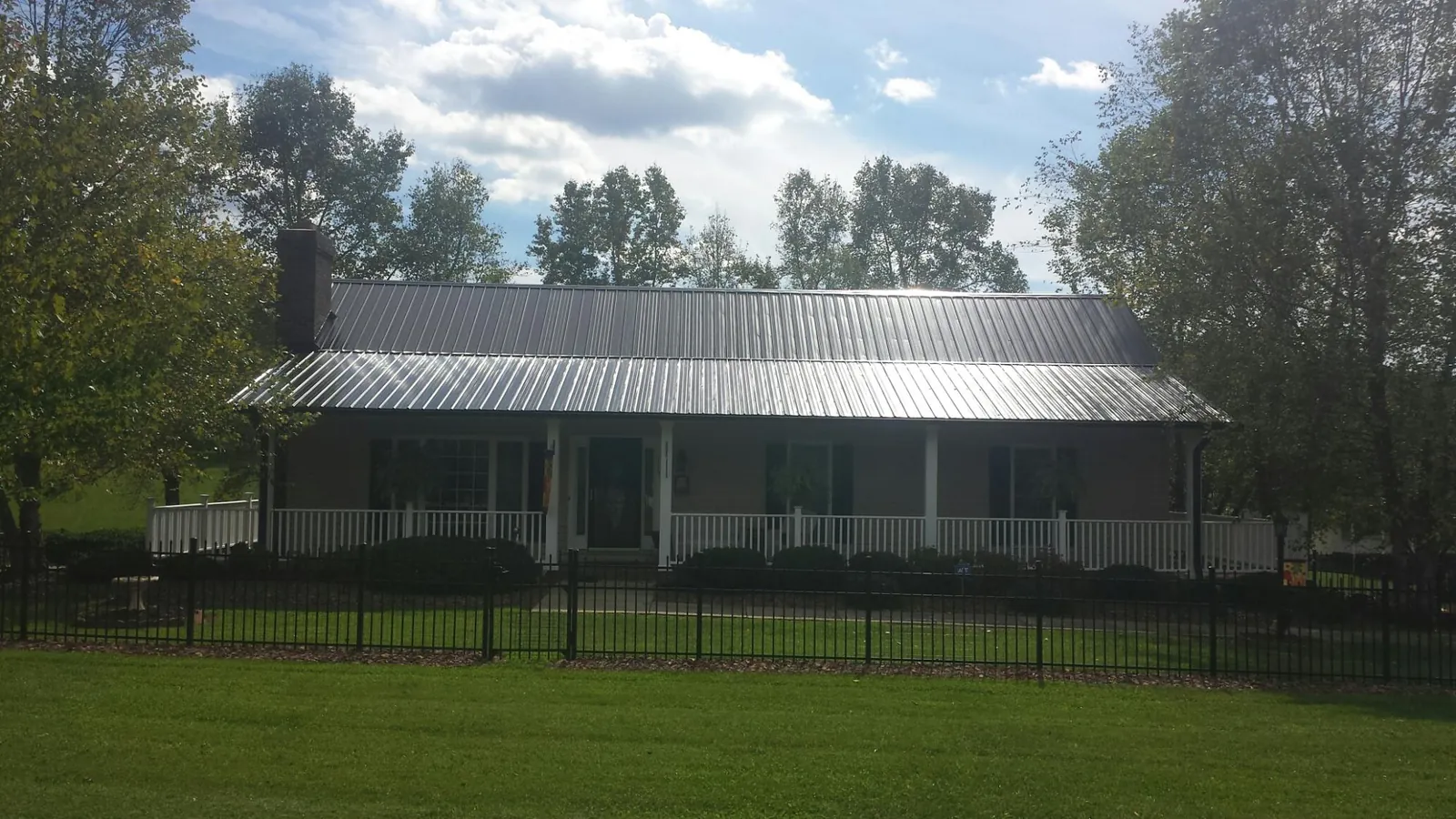 Gray metal roof on a brick ranch with a full width front porch — Gutter Guard Installation work by our crew in Chester Springs