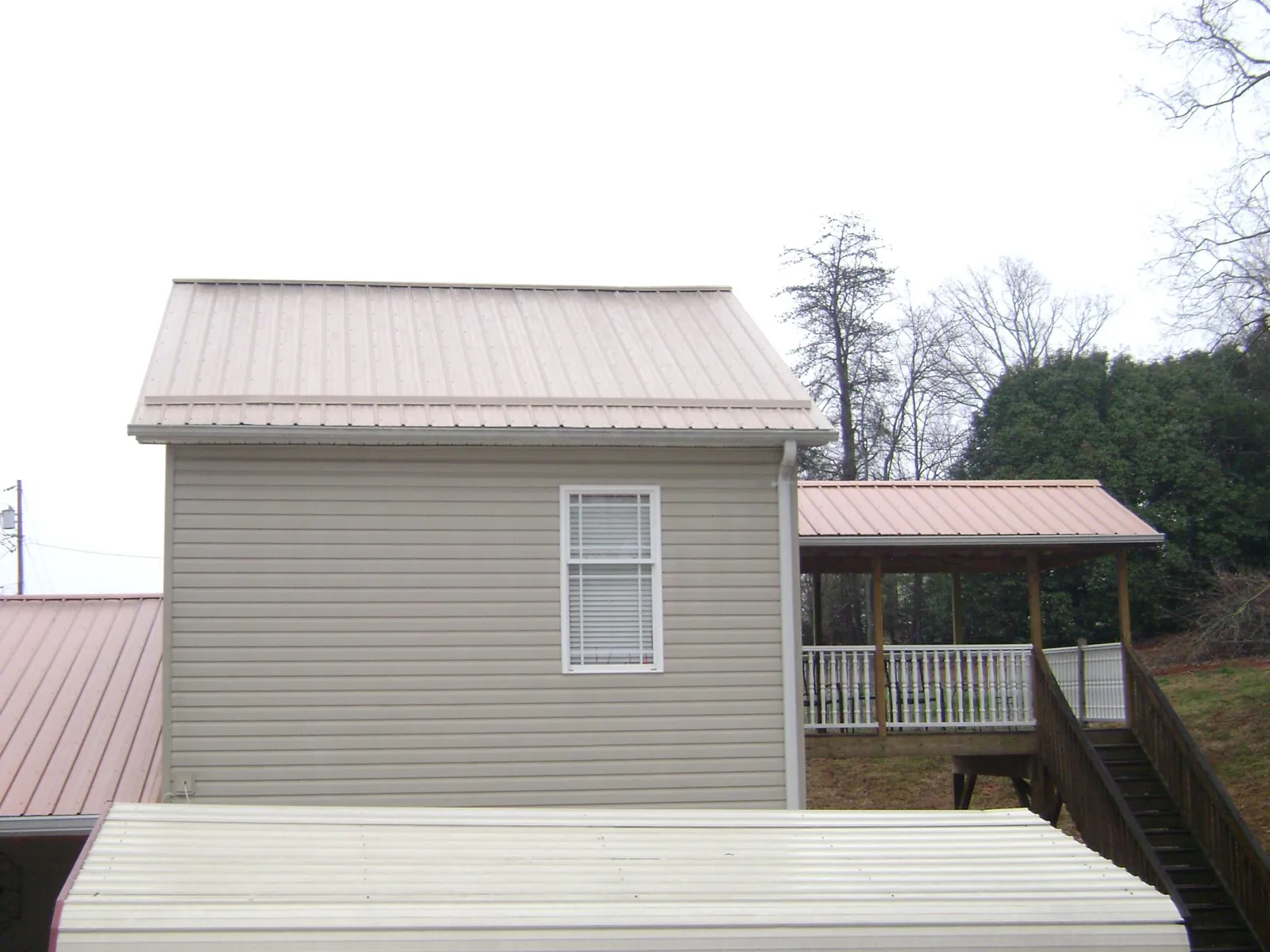 Tan metal roofs on a two story addition and attached porch, from a Roof Replacement job in Chester Springs