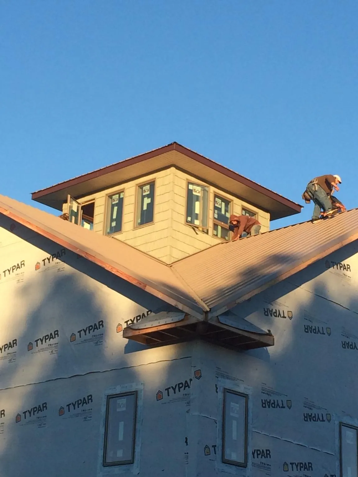 Roofers working around a rooftop cupola on a new metal roof at sunset — Roof Waterproofing in Chester Springs by Roofing Brothers